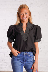 Black v-neck top with white stitching detail