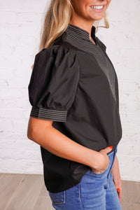 Black v-neck top with white stitching detail