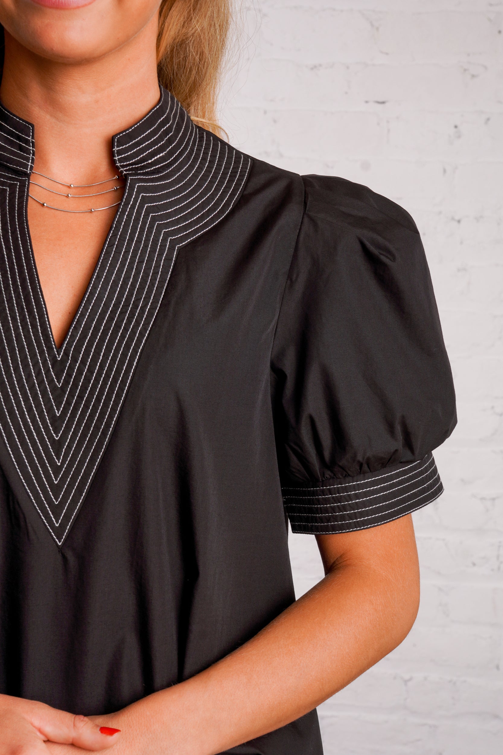 Black v-neck top with white stitching detail