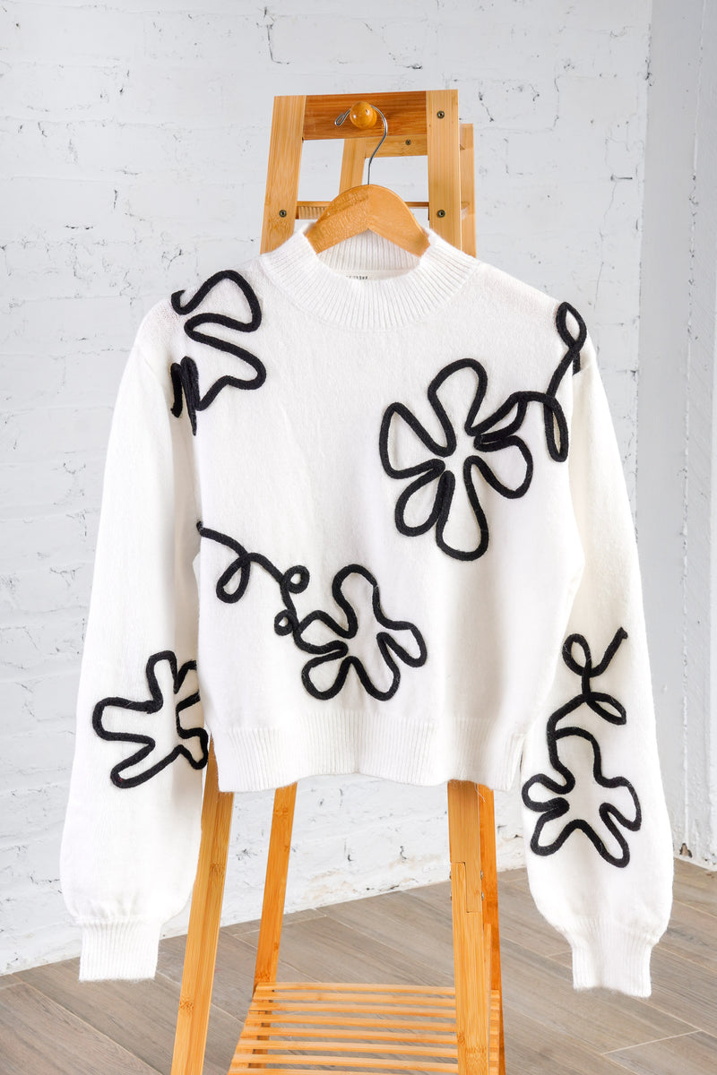 white sweater with black floral outline 