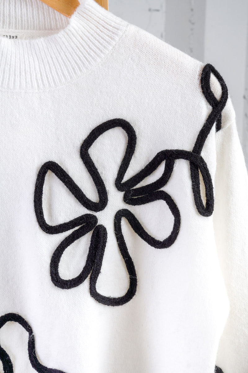 white sweater with black floral outline 