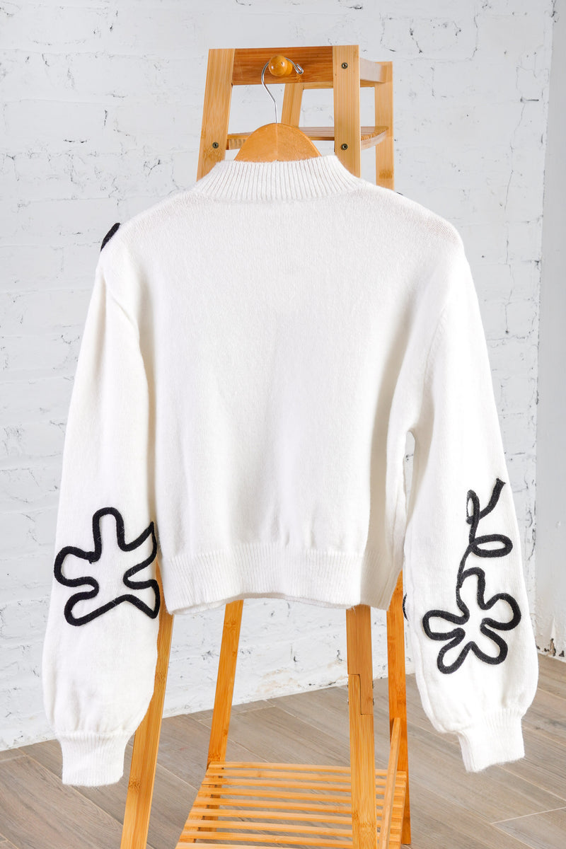 white sweater with black floral outline 