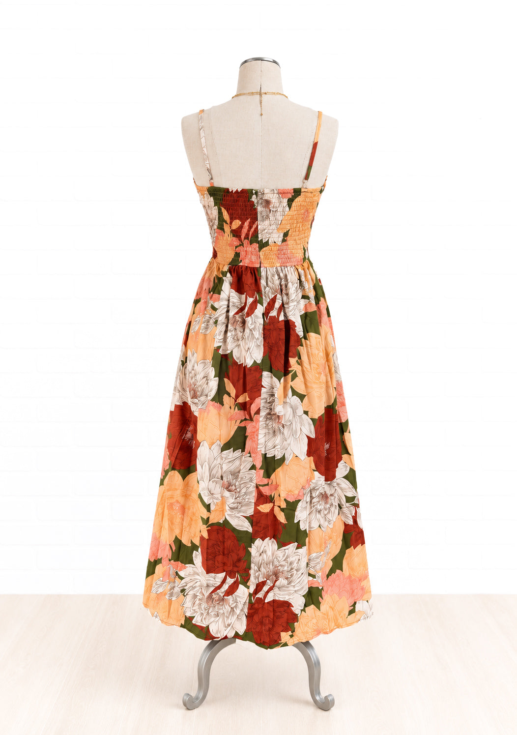 A sleeveless maxi dress with a floral print, displayed on a dress form mannequin against a white background. 