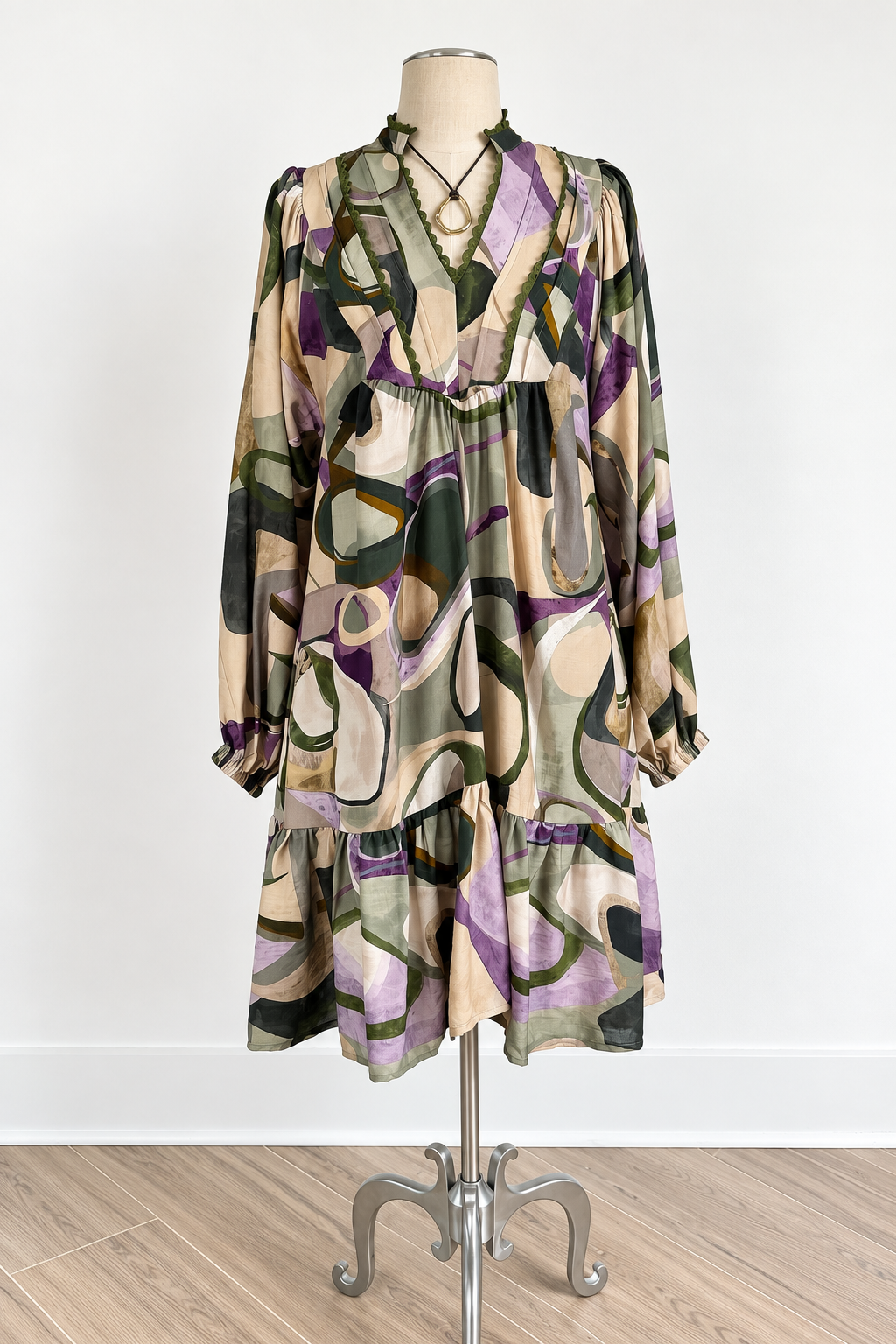 A long-sleeve abstract print dress features a beige, green, purple, and brown organic pattern 