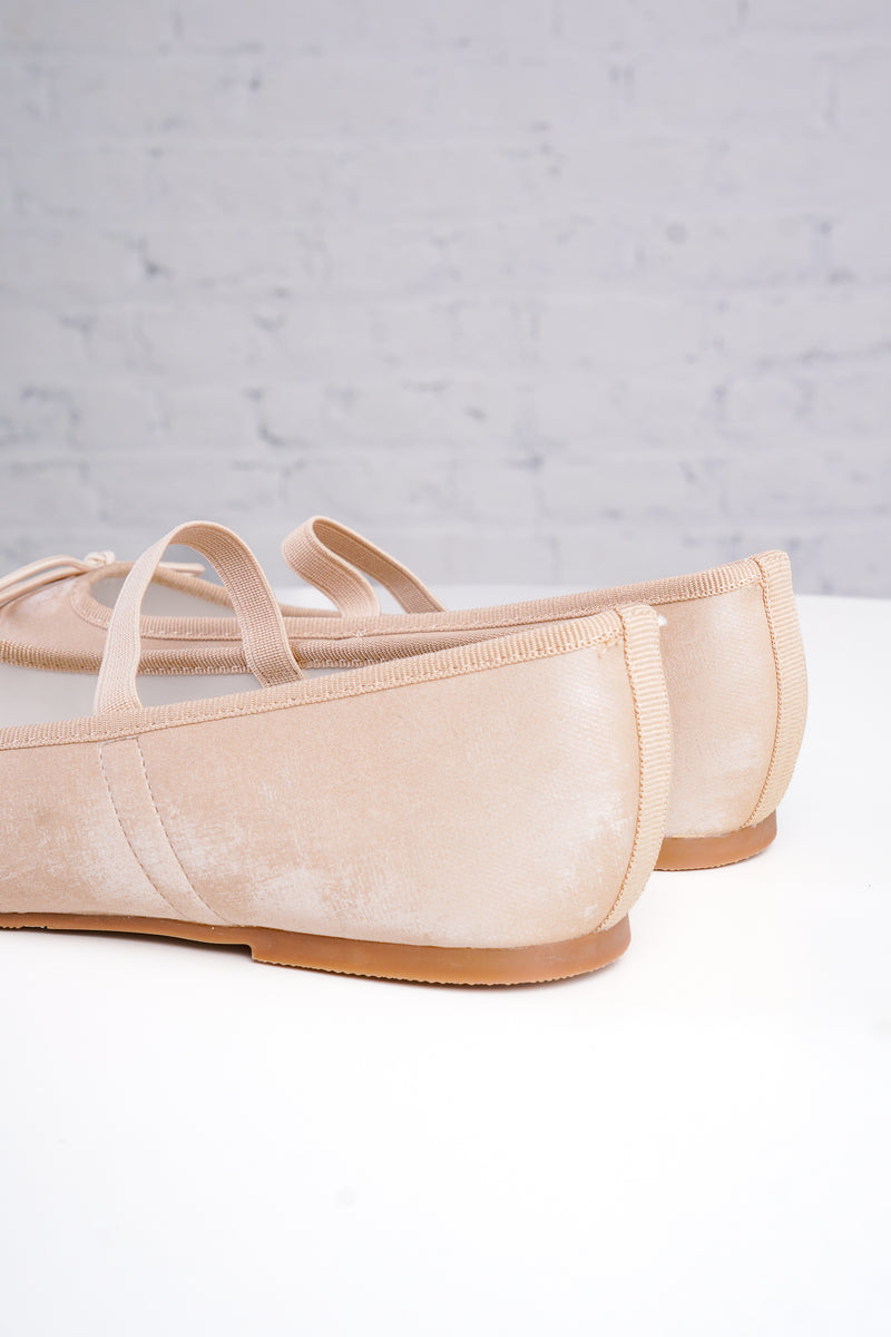 Pair of beige ballet flats on a light gray background