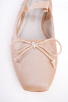 Close-up of a beige ballet shoe with a bow on a white background