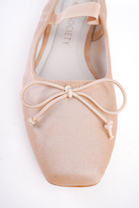 Close-up of a beige ballet shoe with a bow on a white background