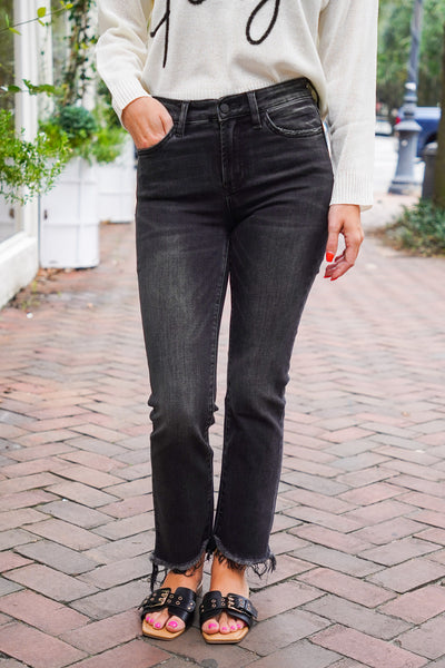 model is wearing black, cropped, denim jeans with distressed hems