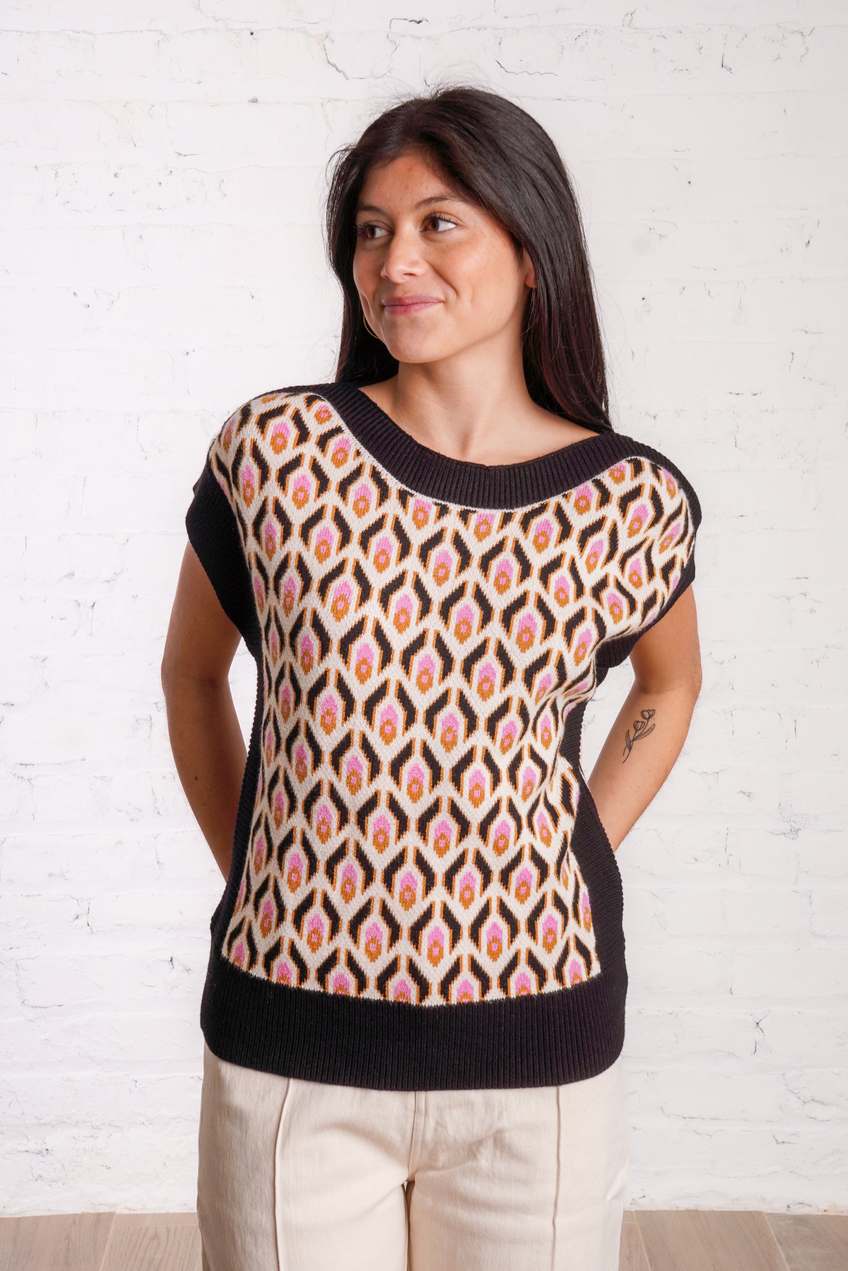 Knitted sweater top with a multicolored retro pattern, and black borders. 