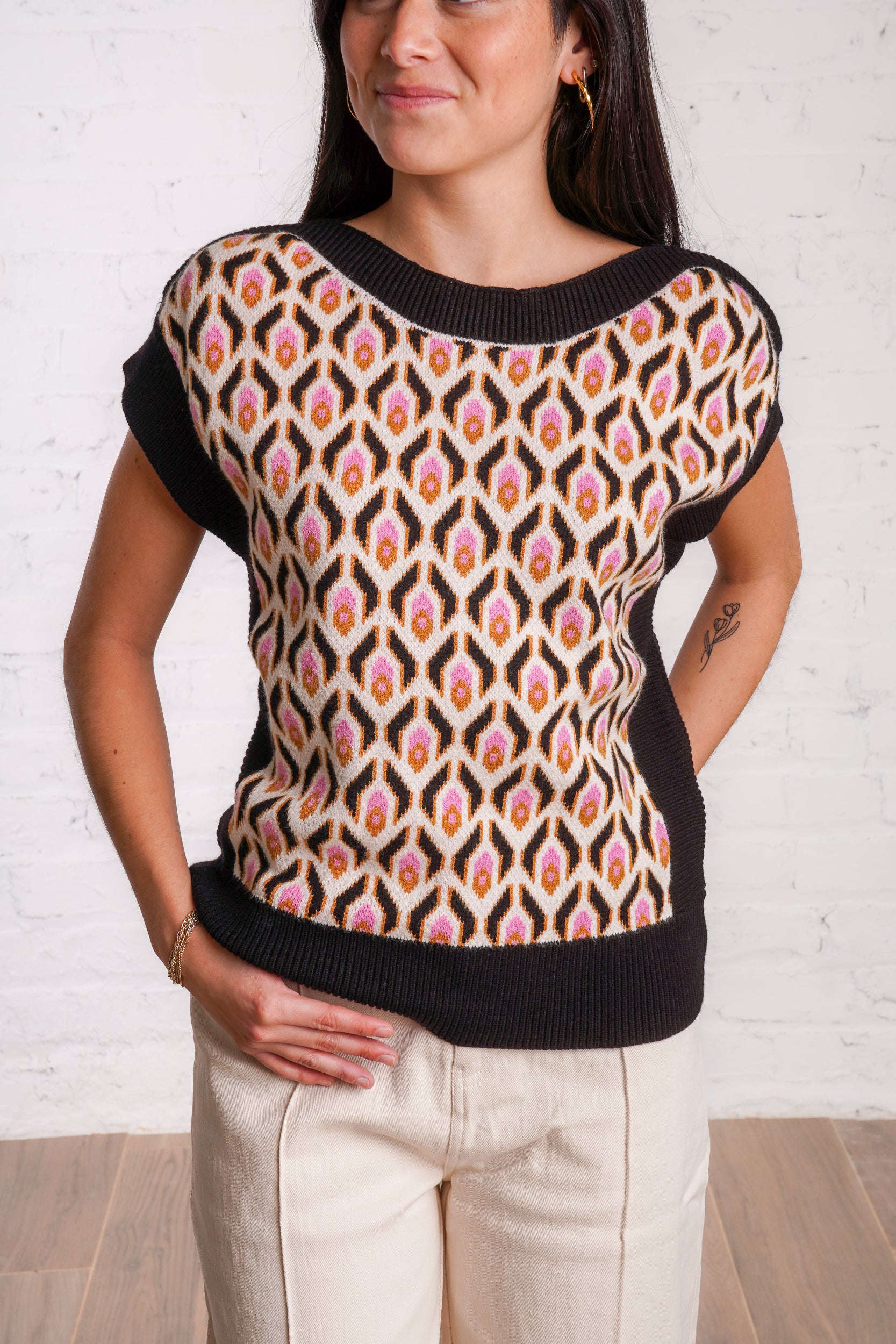 Knitted sweater top with a multicolored retro pattern, and black borders. 
