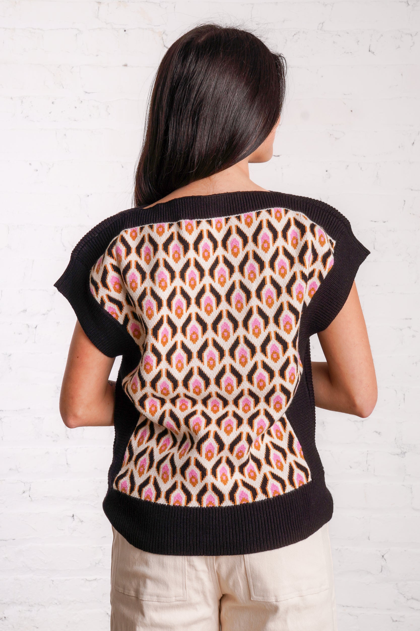 Knitted sweater top with a multicolored retro pattern, and black borders. 