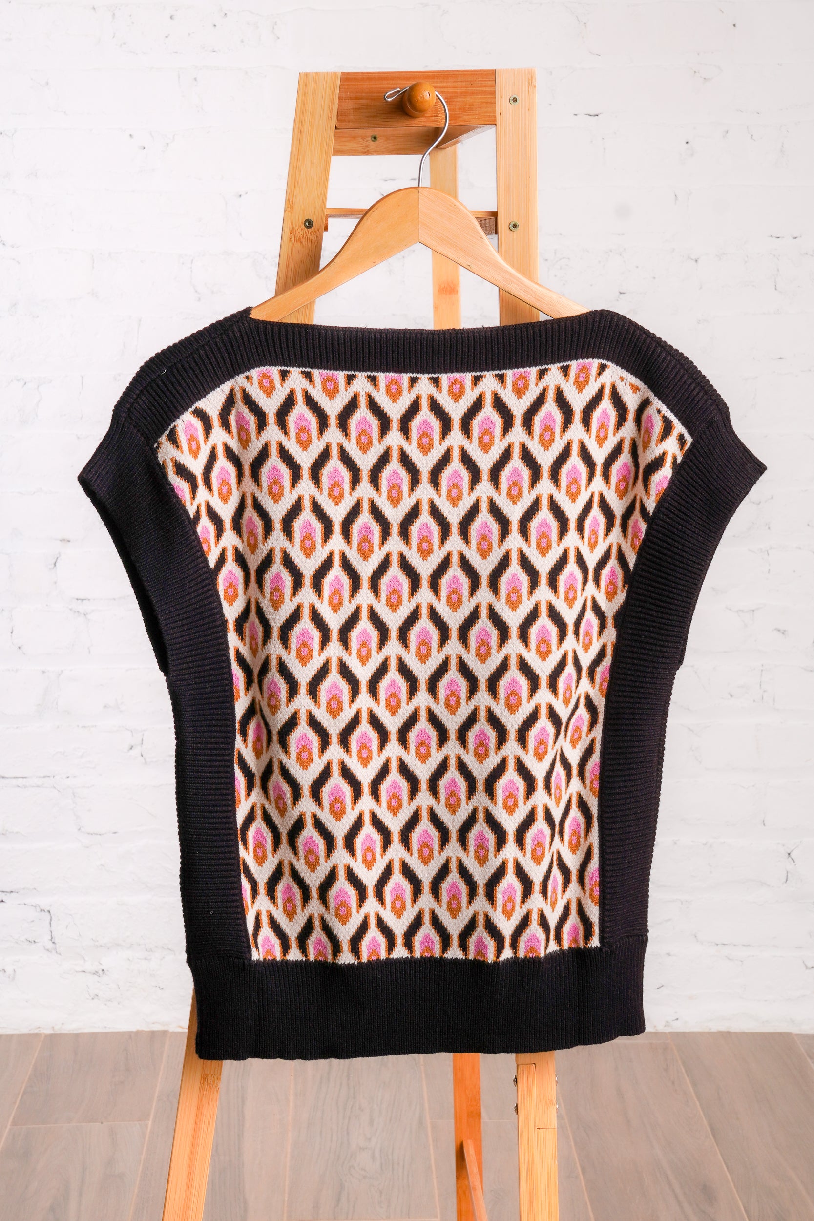 Knitted sweater top with a multicolored retro pattern, and black borders. 