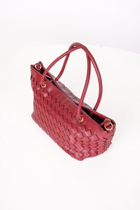 A red woven pleather handbag with double top handles and gold-tone hardware, photographed on a clean white background.
