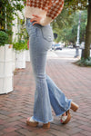 model is wearing light wash, high waisted, denim jeans, with flare legs and distressed hems