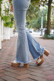 model is wearing light wash, high waisted, denim jeans, with flare legs and distressed hems