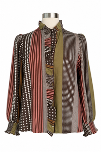 A long-sleeve button-up blouse with a patchwork design of vertical stripes, polka dots, and solid panels in olive green, brown, red, and white, displayed on a mannequin torso against a white background.
