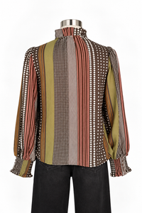 A long-sleeve mock neck blouse with vertical stripes and polka dots in brown, olive green, rust red, and white, displayed on a mannequin torso with black pants against a white background.