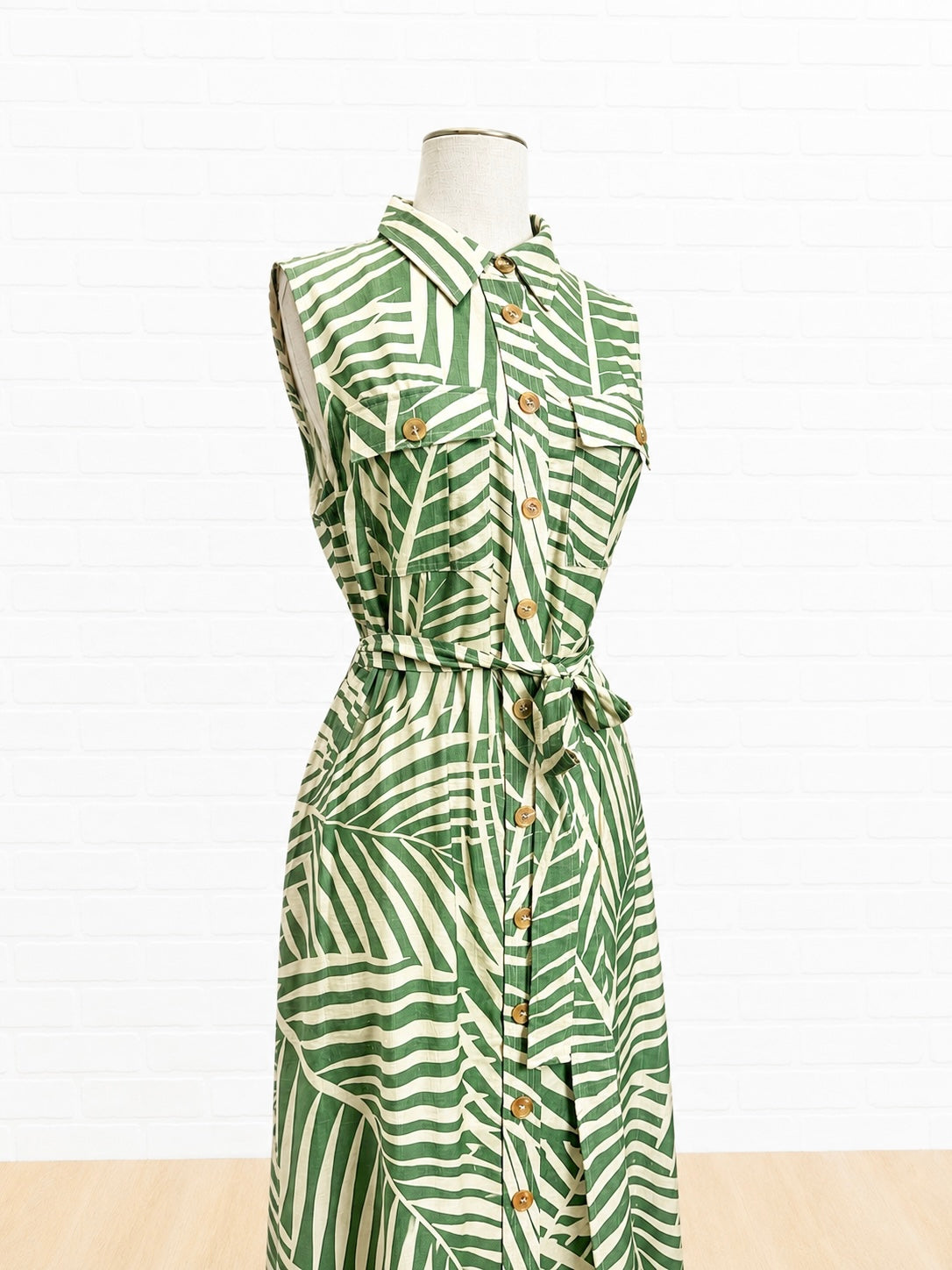 Green and white patterned dress on a mannequin against a white background