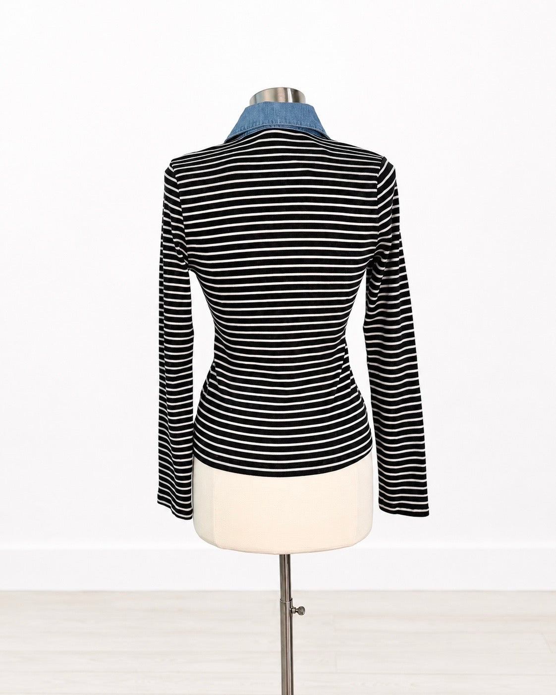 A black and white horizontally striped long-sleeve knit top displayed on a dress form mannequin, featuring a contrasting light blue collar, set against a plain white background.