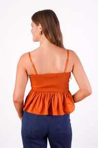 Rusty orange sleeveless top with straps, pleated detailing, peplum, fit, and flare