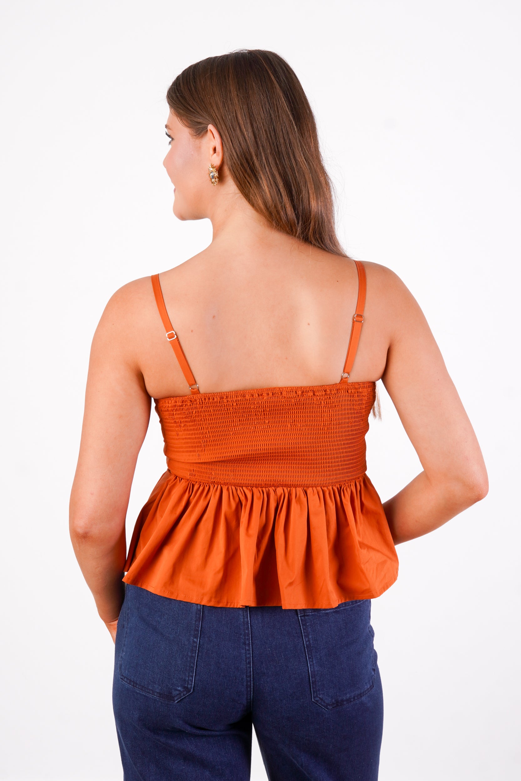 Rusty orange sleeveless top with straps, pleated detailing, peplum, fit, and flare