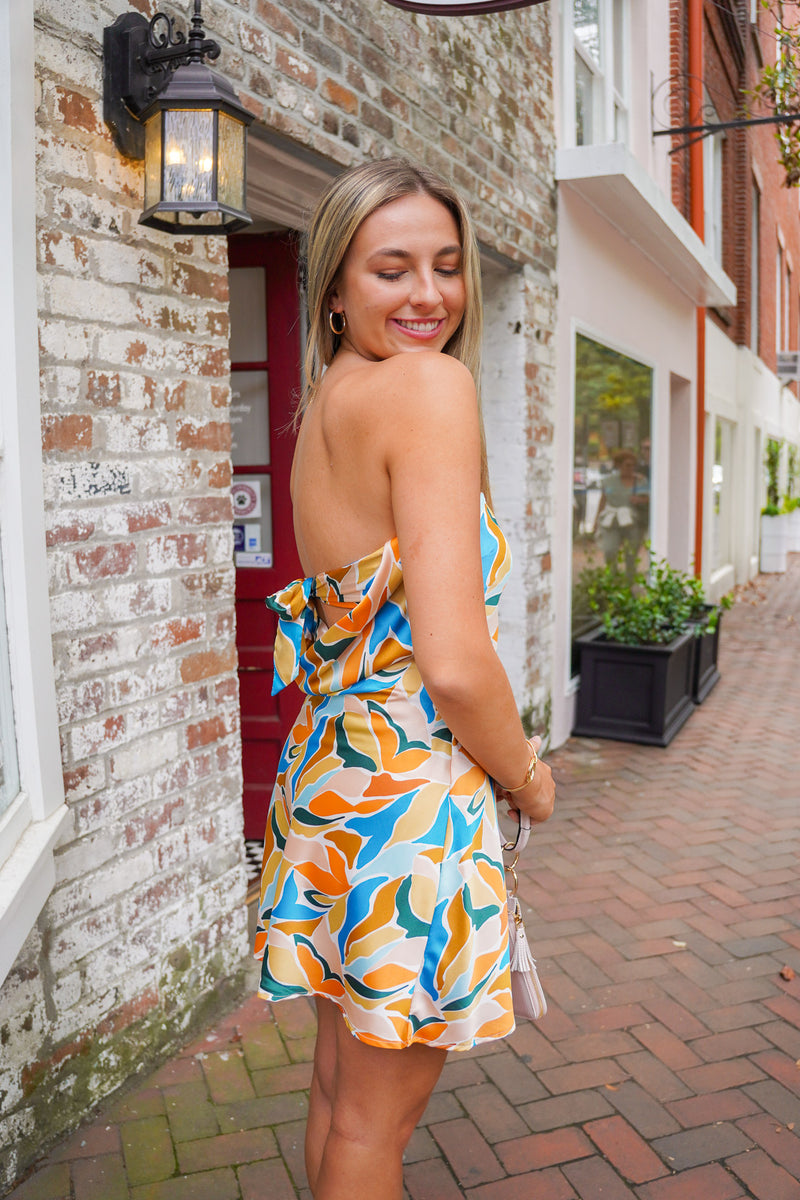 model is wearing a strapless mini dress in front of red clover storefront.