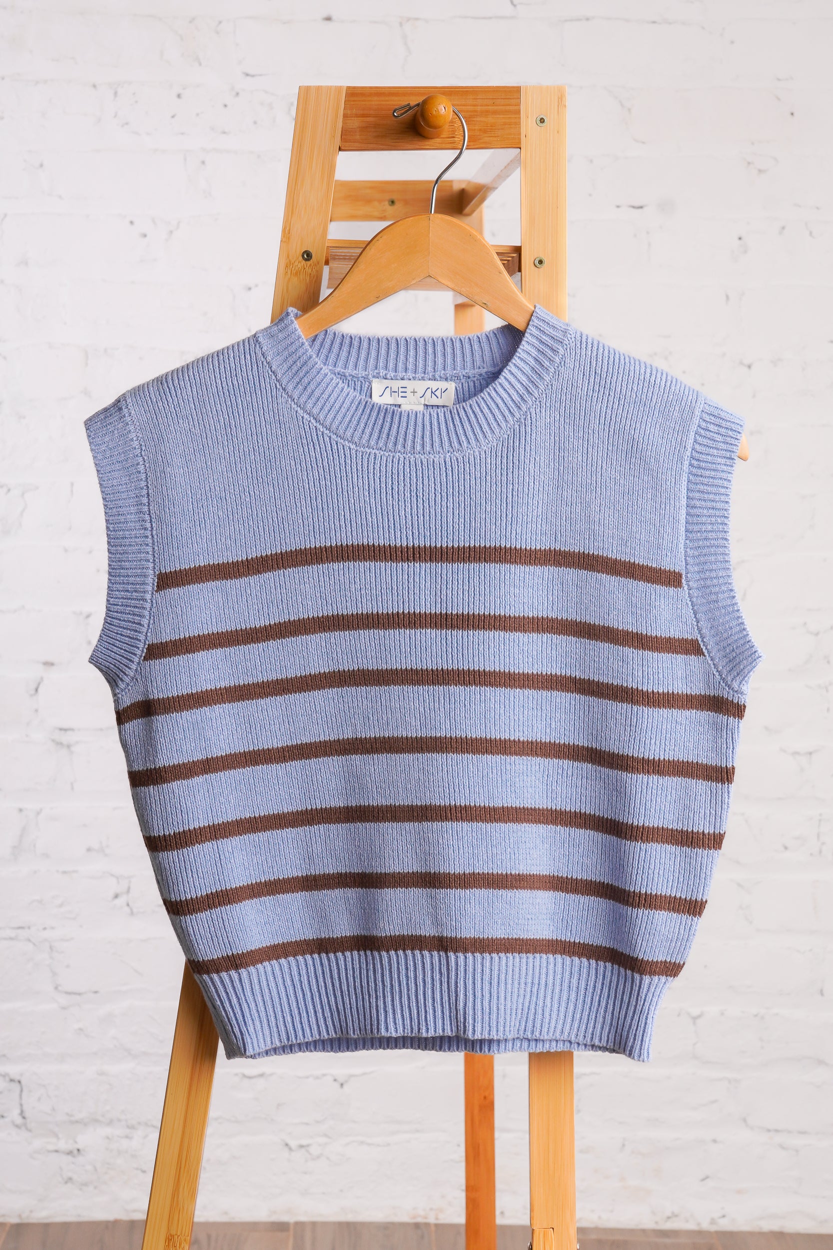 Sleeveless, crew neck, sky blue sweater vest with brown horizontal stripes. 