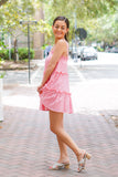 Model is wearing a pink mini dress on a downtown street with a gold purse