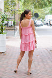 Model is wearing a pink mini dress on a downtown street with a gold purse