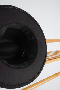 Picture shows a black felt hat with a thin, brown, faux leather band around the head. 