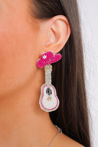 Model is wearing pink guitar shaped earrings