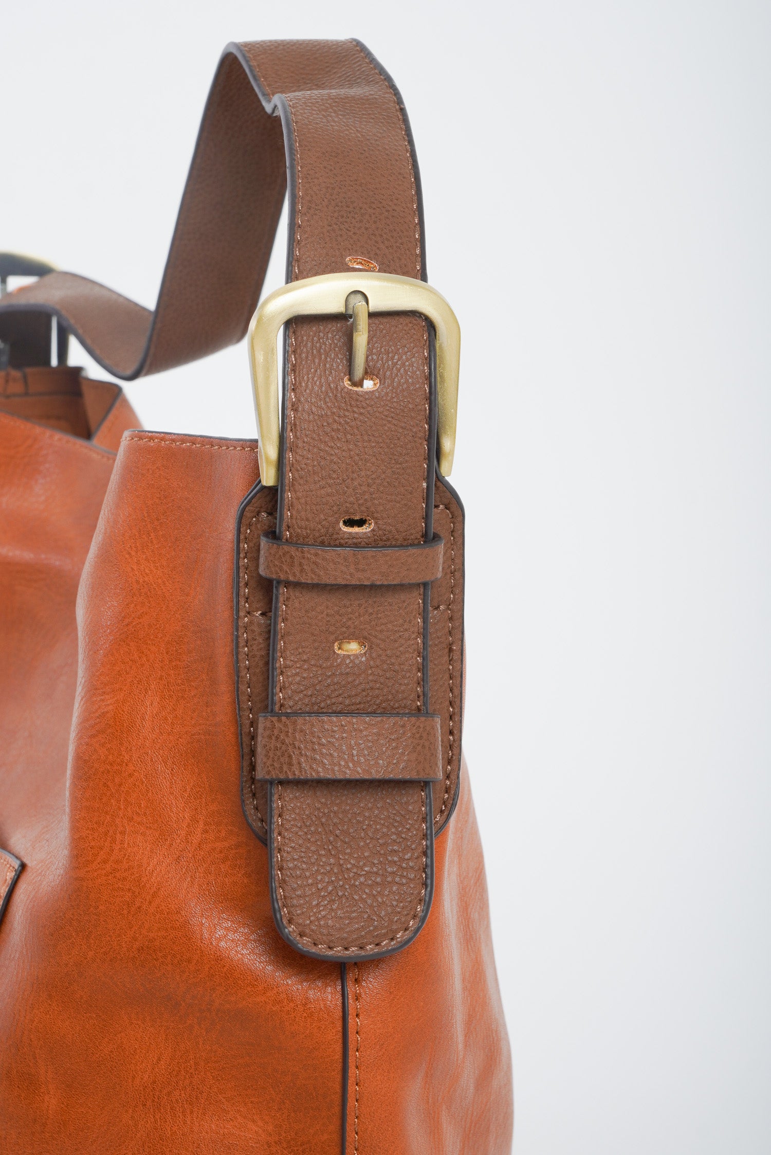 A two toned brown hobo bag with a snap closure and an adjustable strap. 