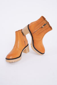 Photo shows a pair of caramel colored lug boots with a gum sole. 
