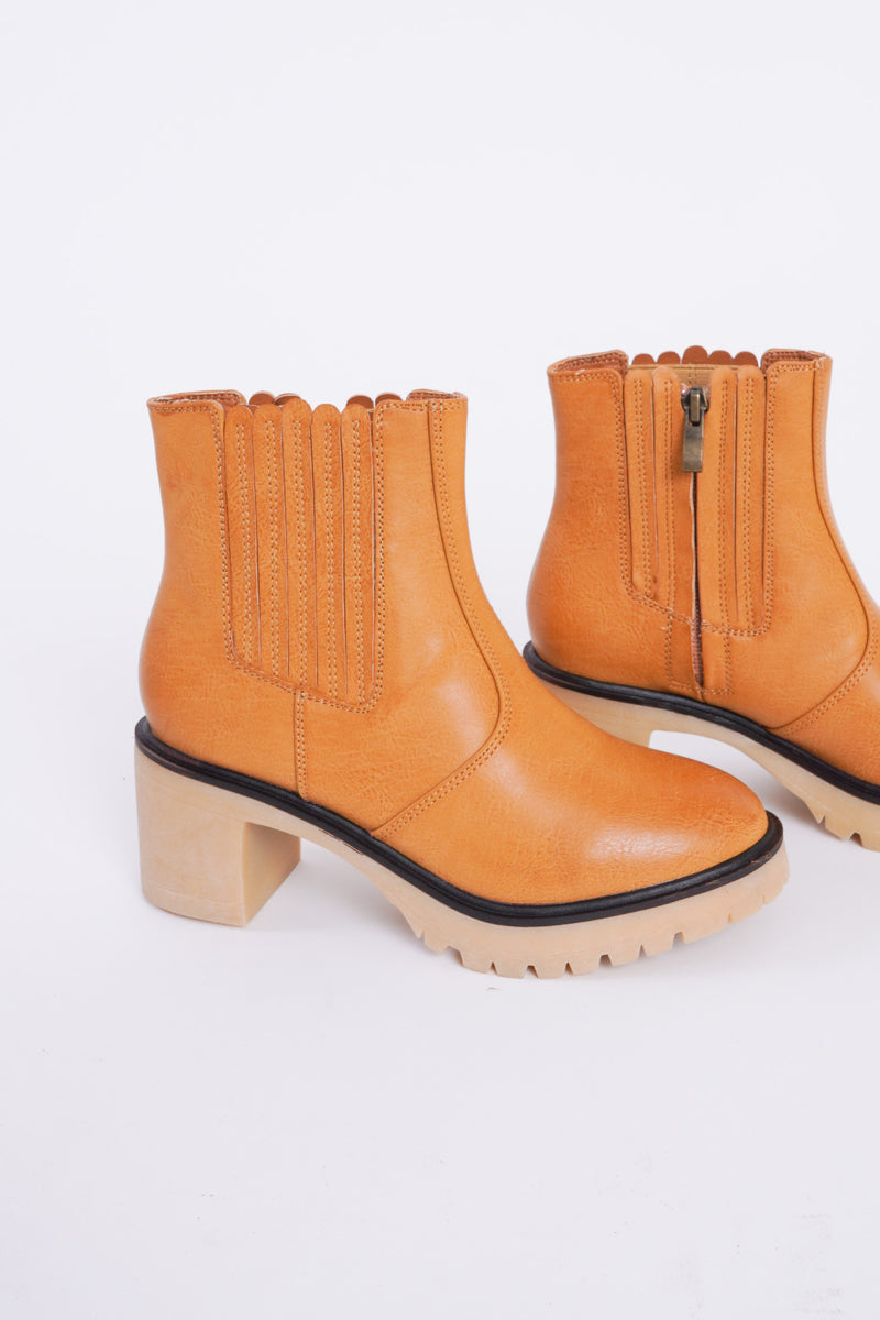 Photo shows a pair of caramel colored lug boots with a gum sole. 