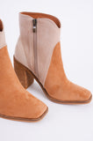 Photo shows a pair of color blocked booties in various neutral shades. 