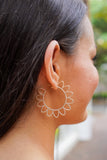 model is wearing gold hoops with patal shapes around the outside of the hoop
