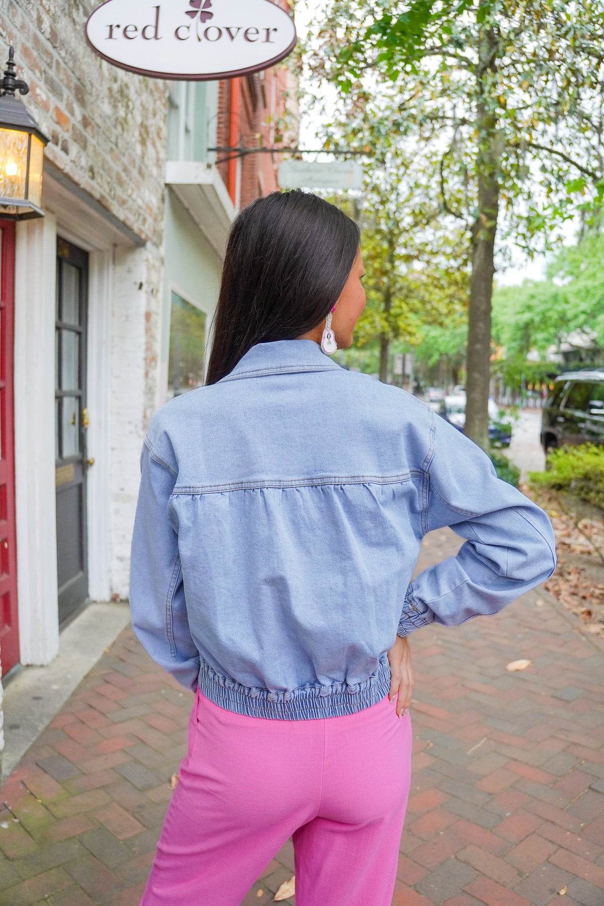 Model is wearing a denim jacket over a white tank with pink linen pants.