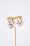 Photo shows a pair of gold mini hoops with various sizes of pearls on the outside of the hoop. 