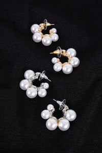 Photo shows a pair of small silver and pearl hoops sitting next to a pair of gold and pearl hoops. 
