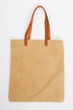 The back side of a brown canvas tote with faux leather straps. 