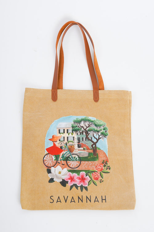 A brown tote bag with a Savannah cityscape motif on the middle front. 