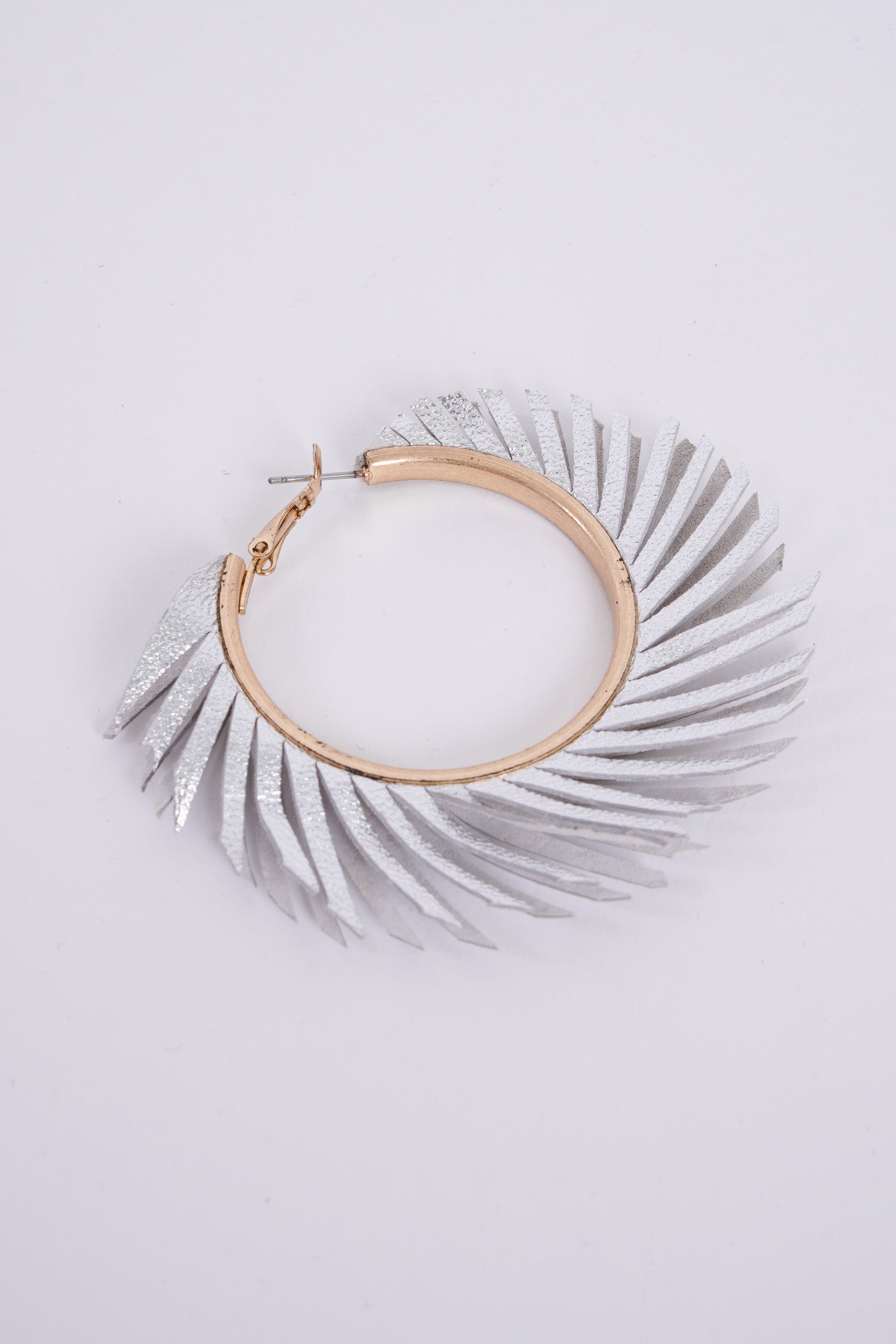 Photo shows a pair of faux leather, feather style hoops made from a metallic silver material. 
