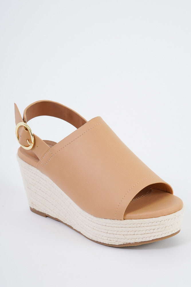 A tan pair of wedge sandals with a thick strap over the top of the foot and a strap with a buckle around the back. 