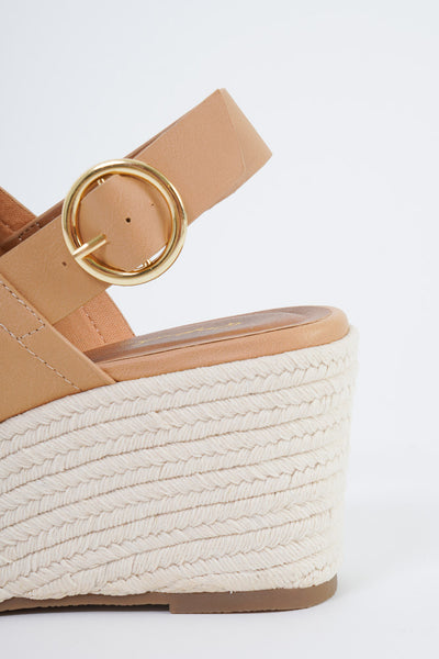 A tan pair of wedge sandals with a thick strap over the top of the foot and a strap with a buckle around the back. 