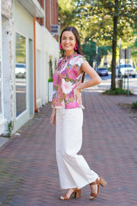Model is wearing white denim flare pants with a floral top and brown heels